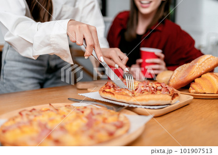 Group of friends drinking beverage and cutting slice of italian 101907513
