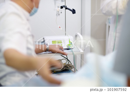 Anesthetist giving anesthesia to patient before operation in a clinic. Anesthesiologist observing the monitor readings while the patient is being anesthetized while surgery operation 101907592