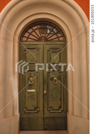 Vintage brown green wooden door with orange wall in Italy 101909355