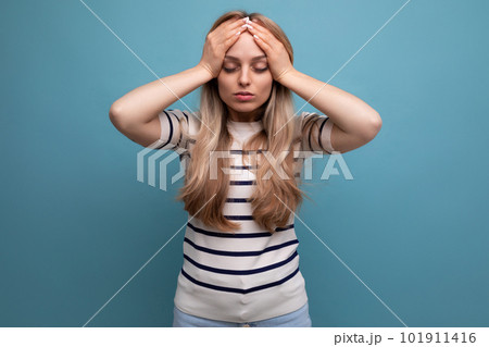 close-up of a sad girl in casual clothes holding her head on a blue isolated background close-up of a sad girl in casual clothes holding her head on a blue isolated background 101911416