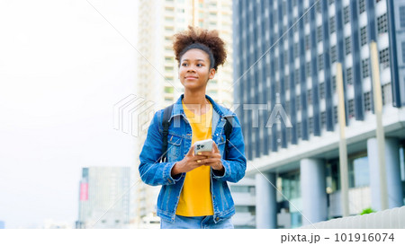 Black young woman, using smart phone and smile with walking in the city outdoor 101916074