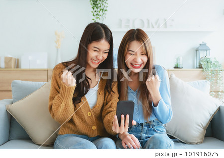 Two asian young women happy smiling and taking selfie in living room at home 101916075