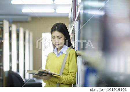 Student standing and reading book at library. Student standing and reading book at library. 101919101