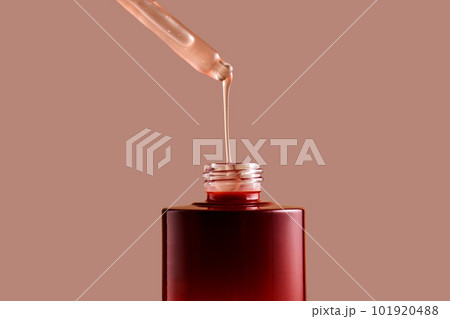 A drop of pink cosmetic drips from the dropper. 101920488