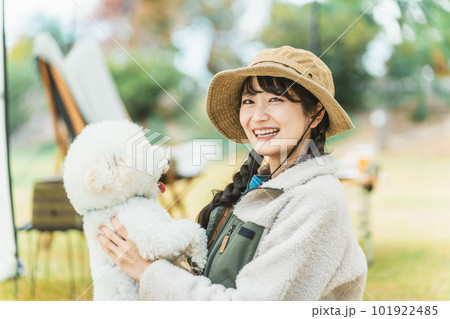 秋冬のキャンプ場で愛犬を抱くキャンパーのアジア人女性(ビジョンフリーゼ) 秋冬のキャンプ場で愛犬を抱くキャンパーのアジア人女性(ビジョンフリーゼ) 101922485