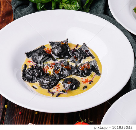 black ravioli with red caviar in white plate 101925032