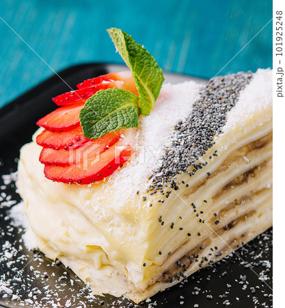 Pancake cake with pieces of strawberries, coconut and poppy seeds and sour cream 101925248