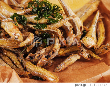 Hot fried smelt fish with salt and herbs on brown paper 101925252