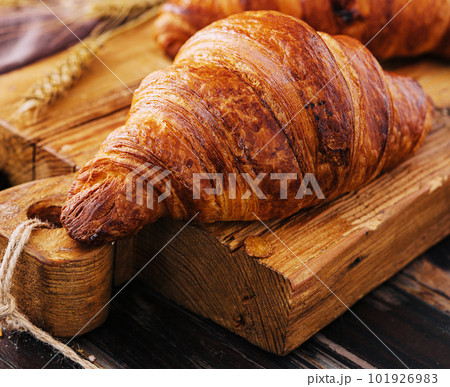 Board with tasty croissants and pastries on table 101926983