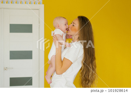 Loving mother holds her newborn baby in her arms at home. A vivid portrait of a happy mother kissing her little son. Loving mother holds her newborn baby in her arms at home. A vivid portrait of a happy mother kissing her little son. 101928614