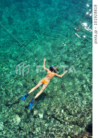 Woman snorkeling in the sea in orange bikini 101928819