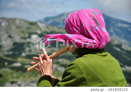 Girl playing on flute in the mountains Girl playing on flute in the mountains 101929123