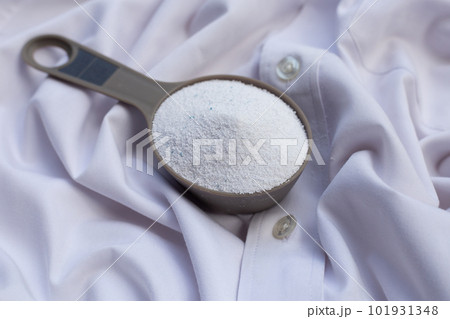 Detergent powder in measuring spoon on cloth before washing. Laundry concept. 101931348