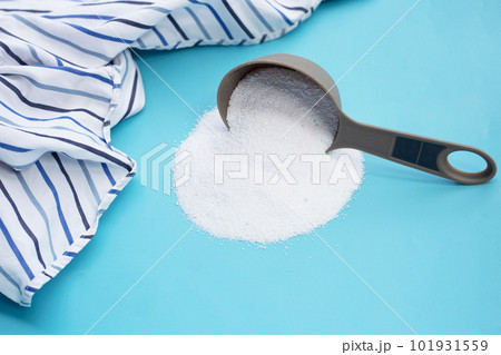 Detergent powder in measuring spoon with cloth before washing. Laundry concept. Detergent powder in measuring spoon with cloth before washing. Laundry concept. 101931559