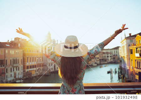 Seen from behind young solo traveller woman in floral dress 101932498