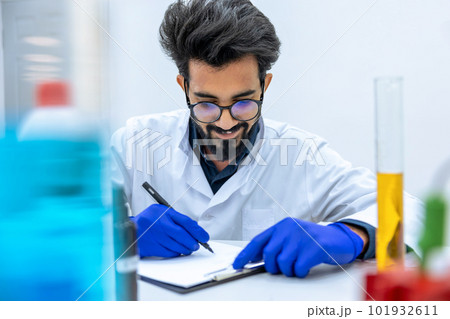 Scientist examining liquid in test tube in laboratory. Scientist examining liquid in test tube in laboratory. 101932611
