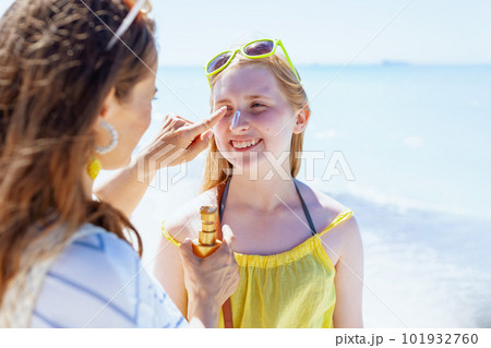 happy modern mother and teenage daughter at beach applying spf 101932760