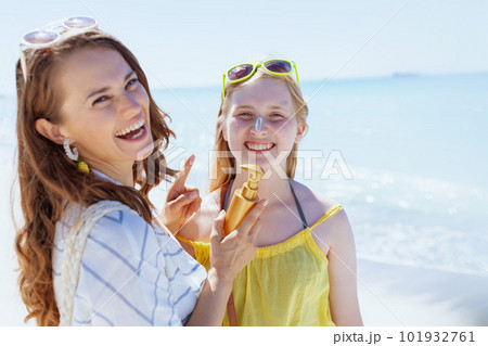 happy modern mother and teenage daughter at beach applying spf 101932761