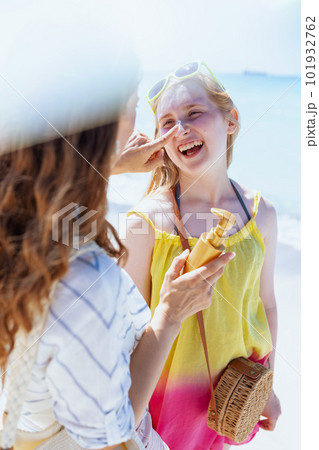 happy mother and teenage daughter at beach applying sunscreen 101932762