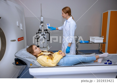Little patient lying on long medical table during MRI scan procedure in hospital. 101933421