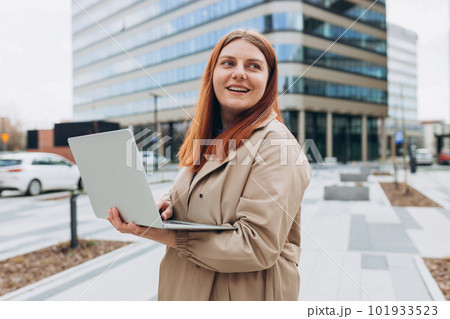 Caucasian businesswoman in fashion office clothes posing outside with a laptop. Successful woman working at laptop. Outdoor office. Business on the go concept. Caucasian businesswoman in fashion office clothes posing outside with a laptop. Successful woman working at laptop. Outdoor office. Business on the go concept. 101933523