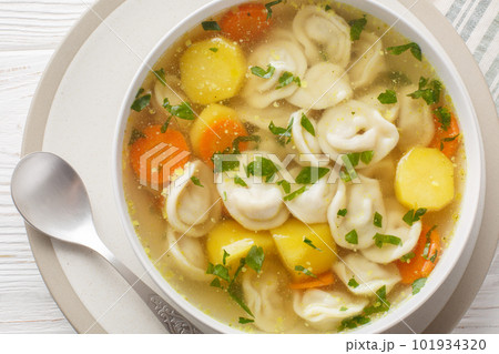 Delicious dumplings soup with carrots, onions, potatoes and chicken broth close-up in a plate. Horizontal top view 101934320