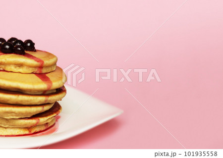 Cropped stack of pancakes with blackcurrant at the top, pink background. Cropped stack of pancakes with blackcurrant at the top, pink background. 101935558