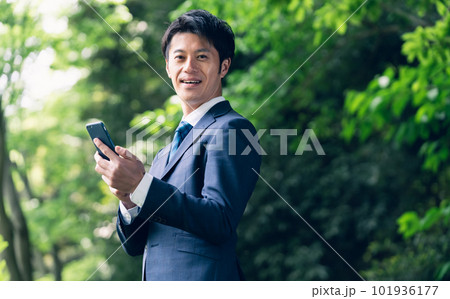 自然の中でスマートフォンを操作するビジネスマン 101936177