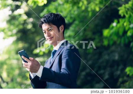 自然の中でスマートフォンを操作するビジネスマン 自然の中でスマートフォンを操作するビジネスマン 101936180