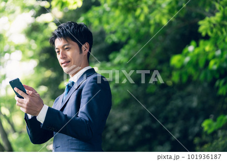 自然の中でスマートフォンを操作するビジネスマン 101936187