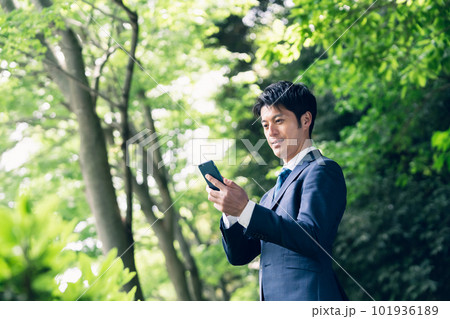 自然の中でスマートフォンを操作するビジネスマン 自然の中でスマートフォンを操作するビジネスマン 101936189