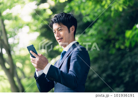 自然の中でスマートフォンを操作するビジネスマン 101936191