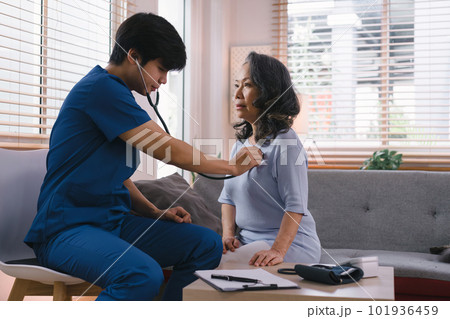 Young Asian male nurse, assisted living in-home carer, or doctor visiting an old senior citizen at home to talk about result follow-up checklist, healthcare advice, or prescription. Young Asian male nurse, assisted living in-home carer, or doctor visiting an old senior citizen at home to talk about result follow-up checklist, healthcare advice, or prescription. 101936459