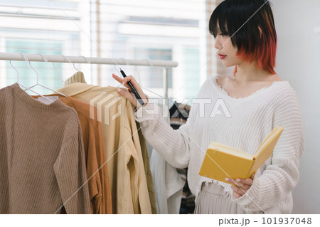 The hipster female fashion designer is working with clothes on a clothing rack in her office and selecting the best option for her customers. This concept relates to fashion and small business. The hipster female fashion designer is working with clothes on a clothing rack in her office and selecting the best option for her customers. This concept relates to fashion and small business. 101937048