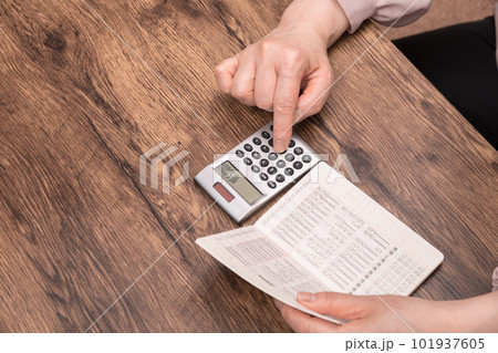 【預金通帳を見ながら計算する主婦】 101937605