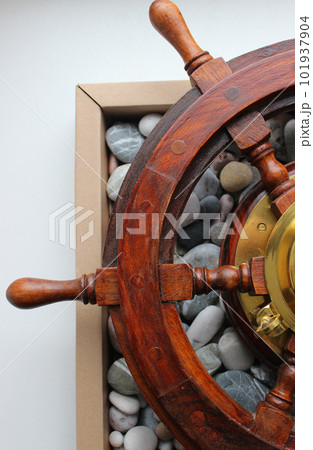 Box With Sea Pebble Stones Under Wooden Ship Steering Wheel Box With Sea Pebble Stones Under Wooden Ship Steering Wheel 101937904