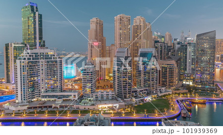 Dubai Marina with several boat and yachts parked in harbor and skyscrapers around canal aerial day to night timelapse. 101939369
