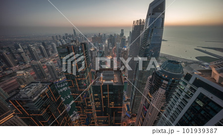 Skyline sunset view of Dubai Marina showing canal surrounded by skyscrapers along shoreline day to night timelapse. DUBAI, UAE 101939387