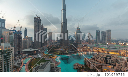 Skyscrapers rising above Dubai downtown day to night timelapse surrounded by modern buildings aerial top view 101939756