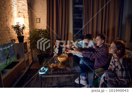 Emotional boys playing online football game on console. Young friends spending time together in evening at home Emotional boys playing online football game on console. Young friends spending time together in evening at home 101940043