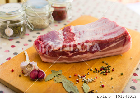 fresh piece of pork belly on wooden board with spices 101941015