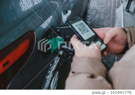 A guy uses his smartphone to pay for gas and fill up his car 101941776