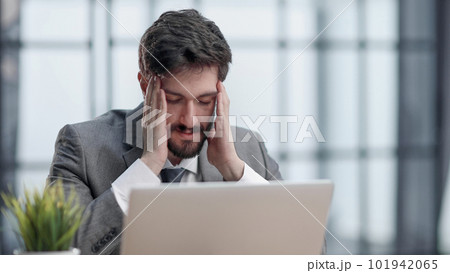 Pensive businessman sitting at the table with laptop 101942065