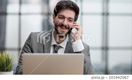 Happy young businessman talking on smart phone at desk in office 101942067