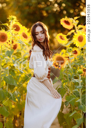 Beautiful woman in a dress in a field of sunflowers Beautiful woman in a dress in a field of sunflowers 101943036
