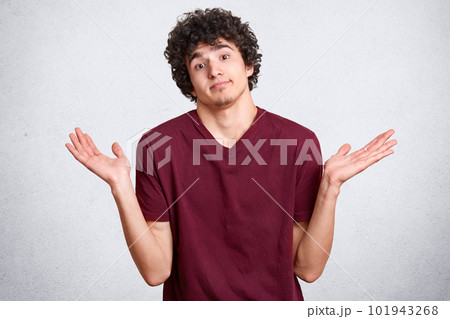 Black haired charismatic pleasant young man with little beard, shrugging hands with desperation, looking directly at camera, raising his arms up, standing isolated over white background in studio. Black haired charismatic pleasant young man with little beard, shrugging hands with desperation, looking directly at camera, raising his arms up, standing isolated over white background in studio. 101943268