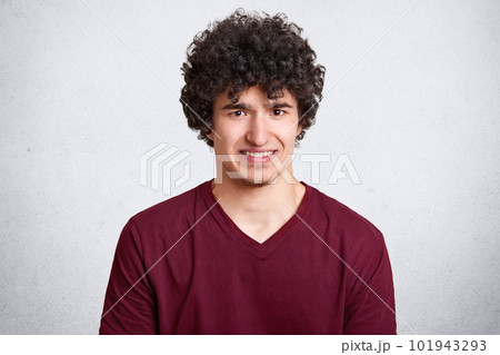 Attractive caucasian male with little beard and in glasses puts fingers in mouth showing disgust about new work with unpleasant people. Facial expression. Isolated over white background. Copy space. 101943293