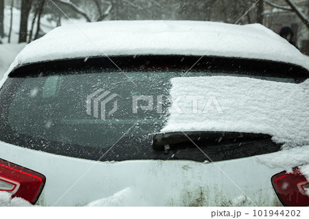 the back door of a crossover half of the window covered with a layer of snow, part of the window is clean, a close-up view of the rear of the vehicle on a winter cold day. 101944202