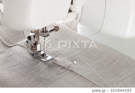 Modern sewing machine presser foot with linen fabric and thread, closeup Modern sewing machine presser foot with linen fabric and thread, closeup 101944393