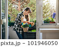 Smiling woman gardening on her balcony with cat 101946050
